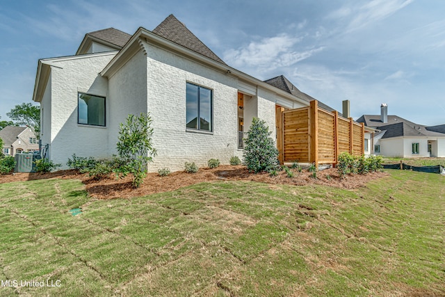 view of side of home with a lawn and central air condition unit