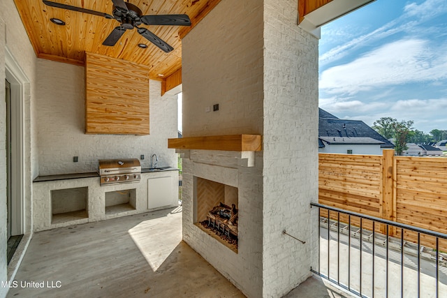 view of patio with sink, an outdoor stone fireplace, ceiling fan, a grill, and area for grilling