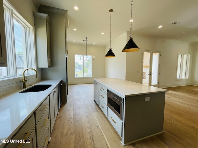 kitchen featuring a kitchen island, pendant lighting, sink, stainless steel appliances, and light hardwood / wood-style flooring