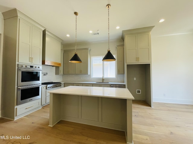 kitchen with appliances with stainless steel finishes, backsplash, light hardwood / wood-style floors, a kitchen island, and wall chimney exhaust hood