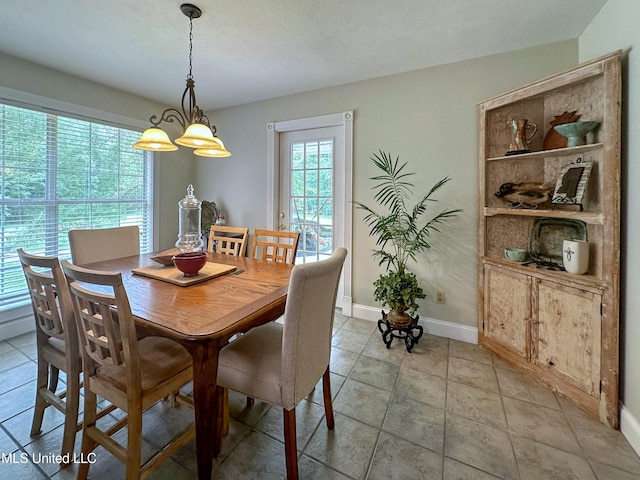 dining area with a textured ceiling, a chandelier, and light tile patterned floors