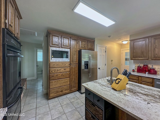 kitchen featuring stainless steel appliances, light stone countertops, and light tile patterned flooring