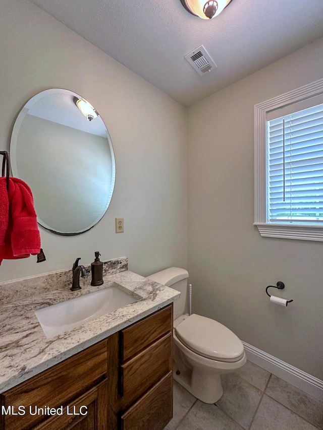 bathroom with toilet, vanity, and tile patterned floors