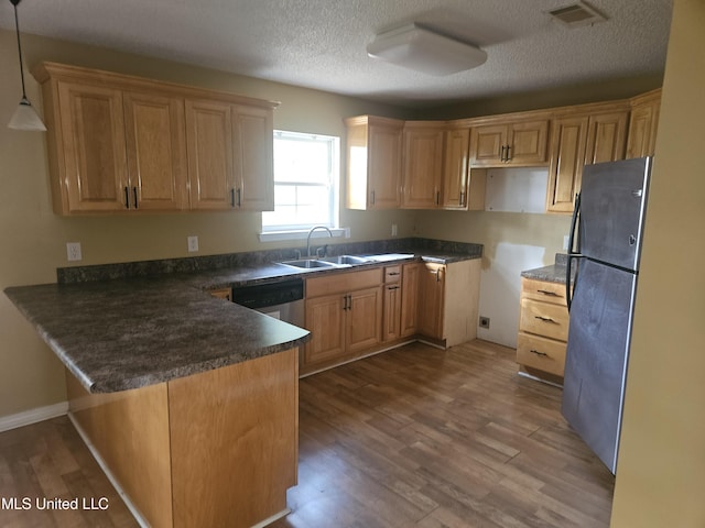 kitchen featuring pendant lighting, a textured ceiling, sink, black fridge, and kitchen peninsula