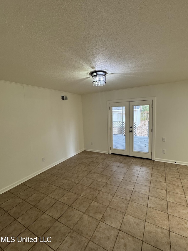 tiled empty room featuring a textured ceiling and french doors