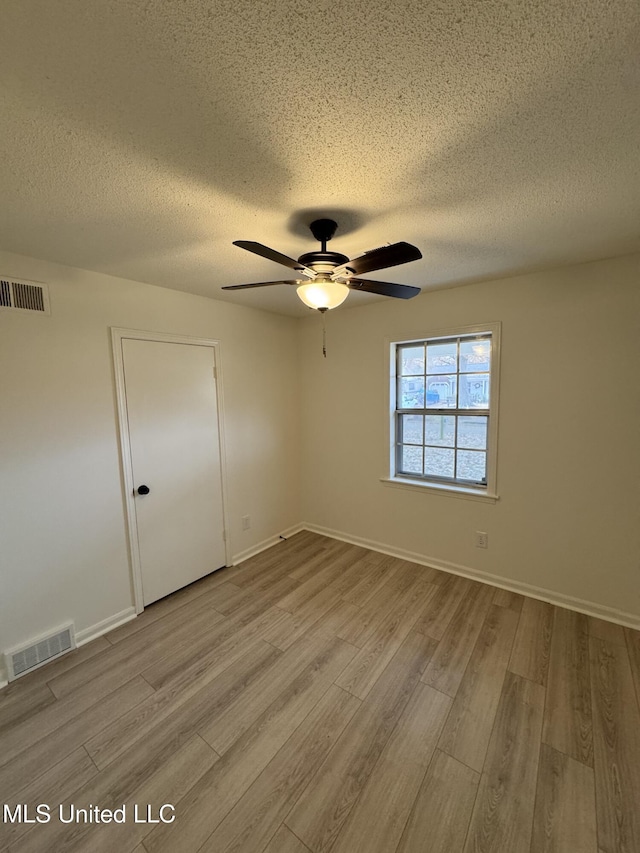 spare room with a textured ceiling, light hardwood / wood-style flooring, and ceiling fan