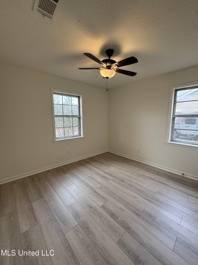 spare room featuring ceiling fan, light hardwood / wood-style flooring, and a textured ceiling