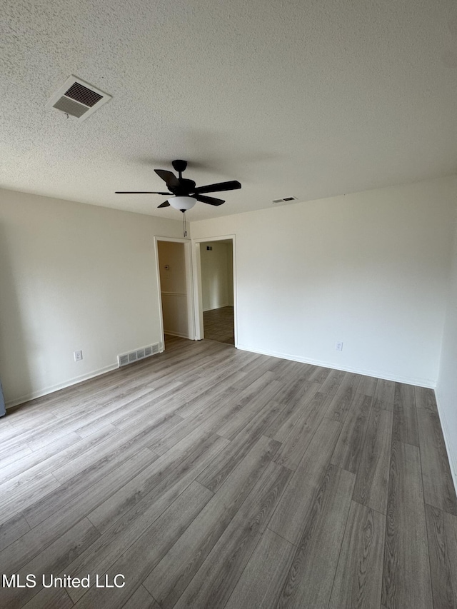 empty room with ceiling fan, a textured ceiling, and light hardwood / wood-style flooring