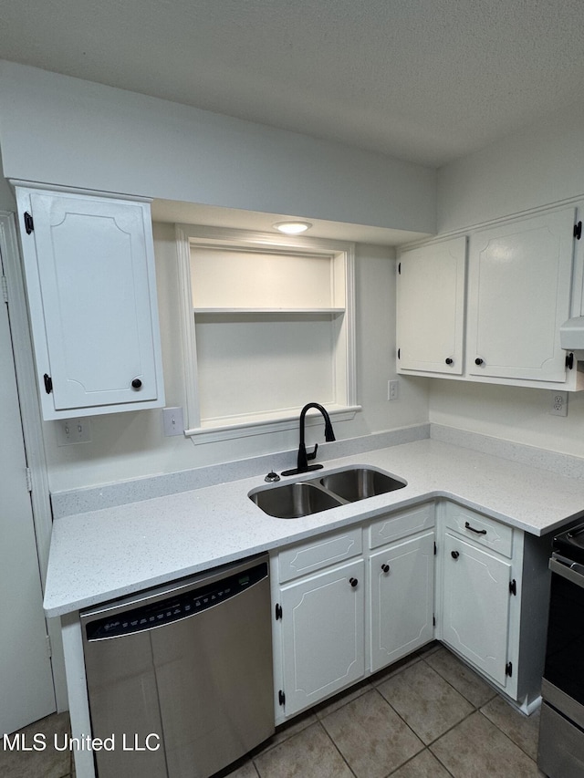 kitchen featuring sink, stainless steel appliances, light tile patterned floors, a textured ceiling, and white cabinets