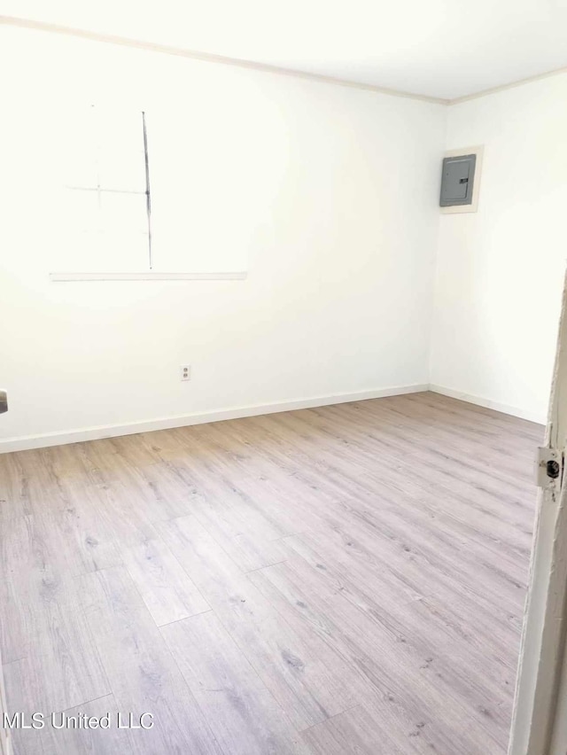 empty room with electric panel, baseboards, and wood finished floors