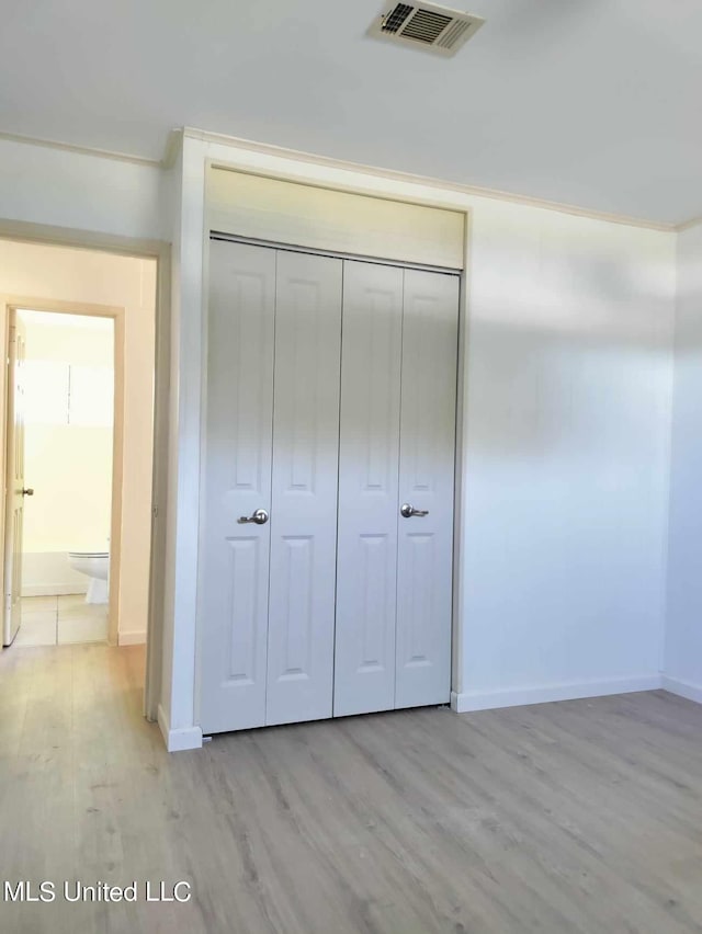 unfurnished bedroom with baseboards, a closet, visible vents, and light wood-style floors