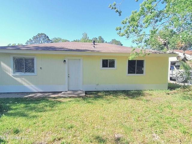 rear view of property featuring a lawn