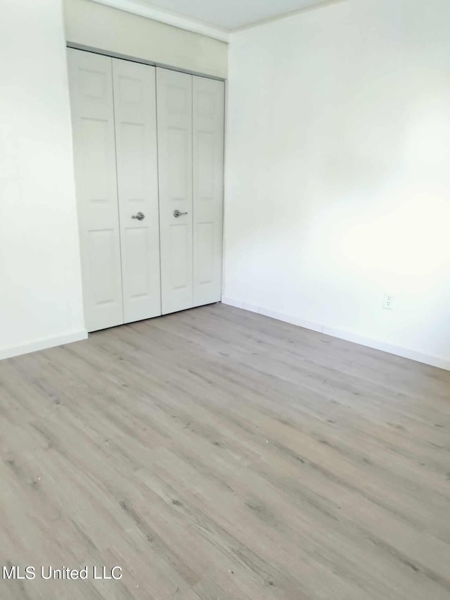 unfurnished bedroom with a closet, baseboards, and wood finished floors