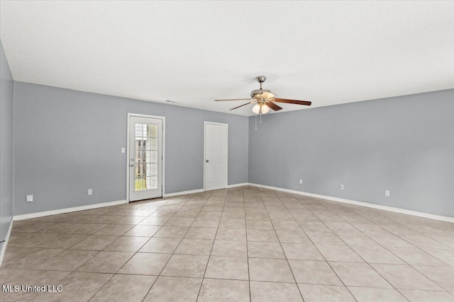 empty room with ceiling fan, light tile patterned floors, and a textured ceiling