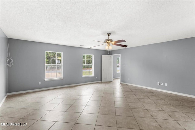 tiled spare room featuring ceiling fan, plenty of natural light, and a textured ceiling