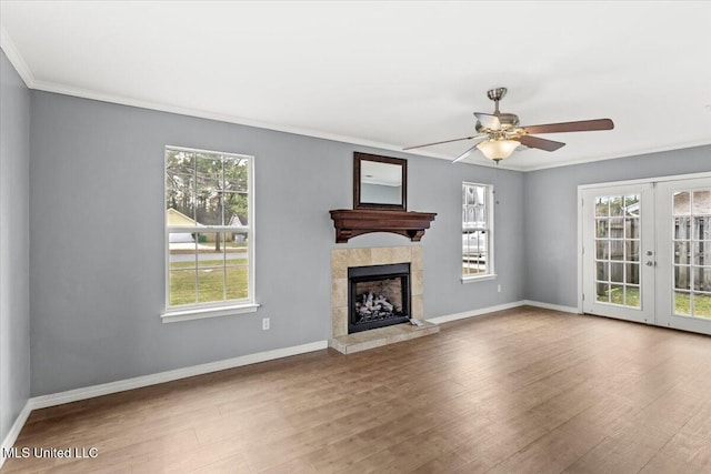 unfurnished living room with french doors, ceiling fan, a healthy amount of sunlight, and a tiled fireplace