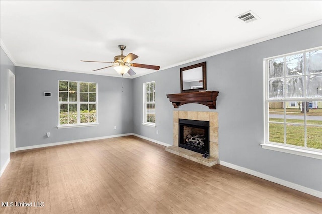 unfurnished living room featuring ceiling fan, light wood-type flooring, ornamental molding, and a tiled fireplace