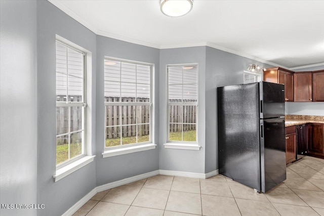 kitchen featuring black refrigerator, light tile patterned floors, and crown molding