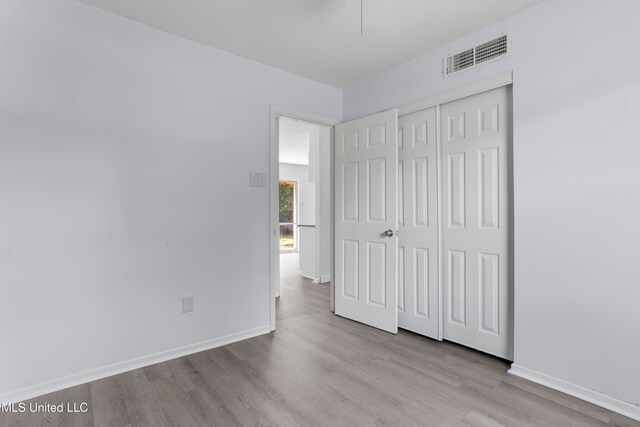 unfurnished bedroom with light hardwood / wood-style flooring and a closet