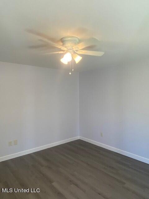 empty room with dark wood-type flooring and ceiling fan