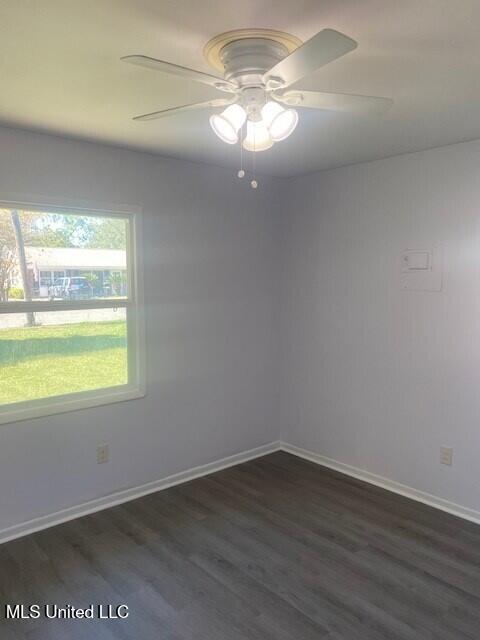 spare room featuring dark wood-type flooring and ceiling fan