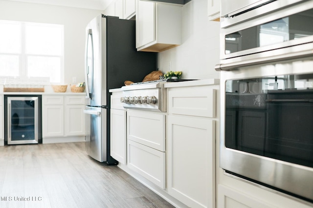 16043 W Dedeaux Rd, Gulfport, MS 39503 - kitchen with beverage cooler, light wood-style floors, light countertops, white cabinets, and oven