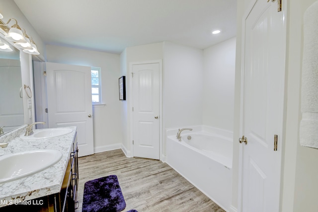 bathroom featuring vanity, a tub to relax in, and wood-type flooring