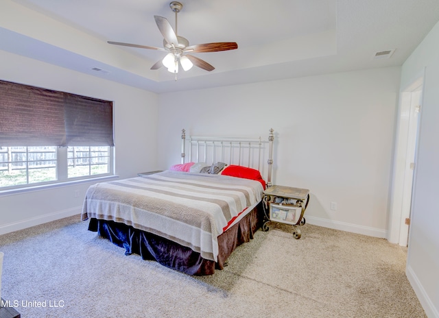 bedroom with carpet, a raised ceiling, and ceiling fan