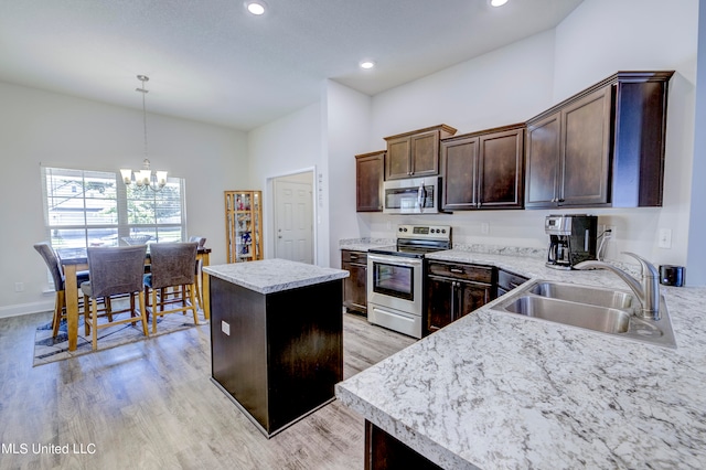 kitchen featuring dark brown cabinets, a kitchen island, appliances with stainless steel finishes, light hardwood / wood-style floors, and sink