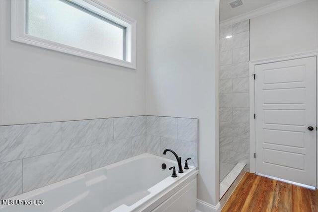 bathroom featuring plus walk in shower, hardwood / wood-style floors, and ornamental molding