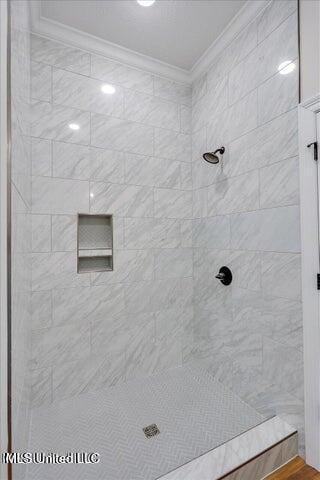 bathroom featuring a tile shower and ornamental molding