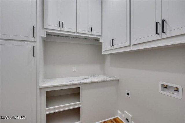 clothes washing area with electric dryer hookup, hookup for a washing machine, cabinets, and light hardwood / wood-style flooring