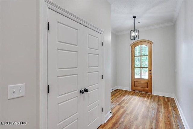 foyer entrance with light hardwood / wood-style floors, crown molding, and a notable chandelier