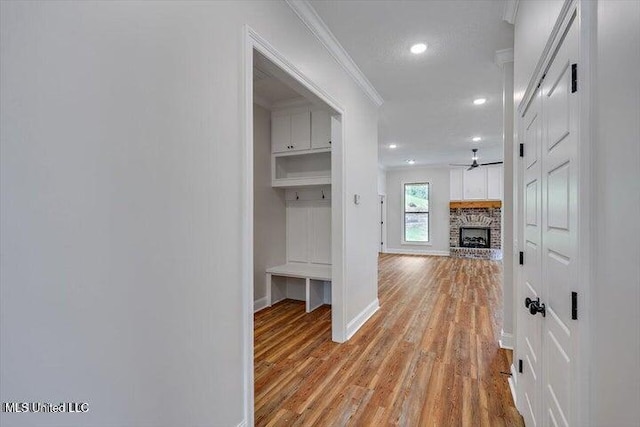 corridor with light hardwood / wood-style floors and crown molding