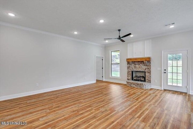 unfurnished living room featuring a textured ceiling, a fireplace, light hardwood / wood-style floors, and a healthy amount of sunlight