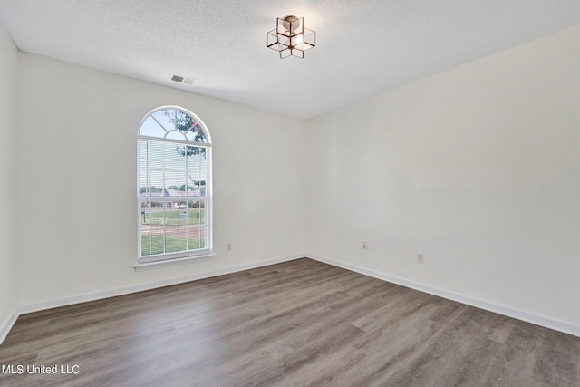 empty room with a textured ceiling and hardwood / wood-style floors