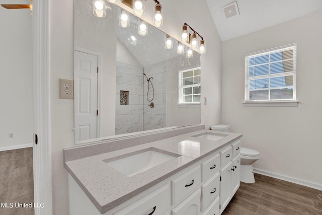 bathroom featuring hardwood / wood-style floors, toilet, lofted ceiling, tiled shower, and vanity