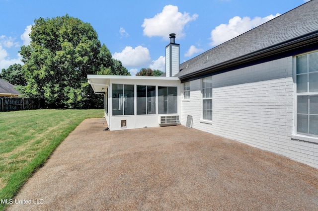 back of property with a patio, a lawn, and a sunroom