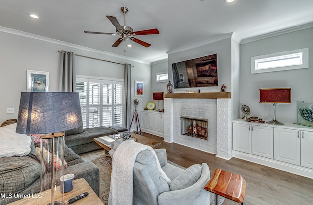 living room featuring crown molding, plenty of natural light, dark wood-type flooring, and a brick fireplace