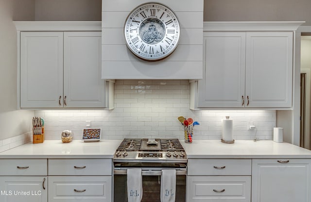 kitchen featuring white cabinetry, stainless steel gas range oven, and backsplash