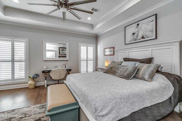 bedroom featuring dark hardwood / wood-style flooring, multiple windows, and a raised ceiling