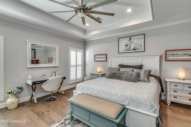 bedroom with ornamental molding, wood-type flooring, and a tray ceiling