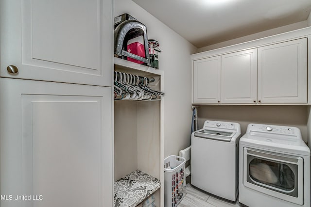 laundry room featuring cabinets, washing machine and clothes dryer, and light wood-type flooring