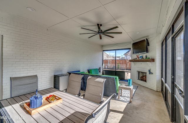 sunroom featuring an outdoor fireplace and ceiling fan