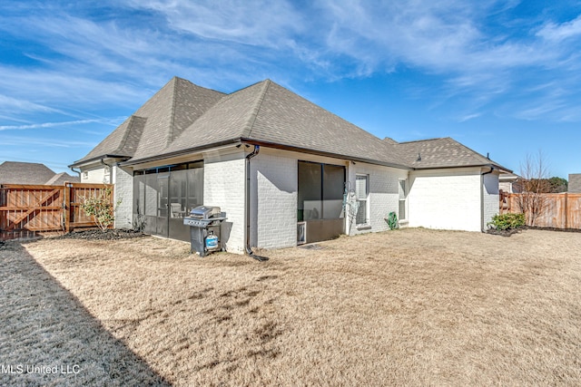 rear view of property featuring a sunroom and a lawn