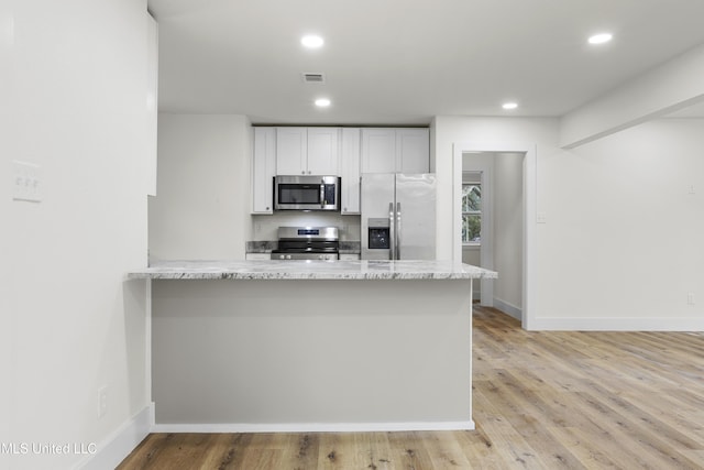 kitchen with light hardwood / wood-style floors, stainless steel appliances, kitchen peninsula, and white cabinets