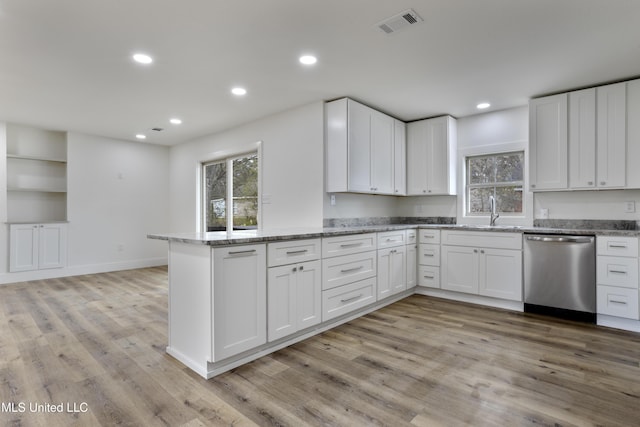 kitchen featuring stone counters, white cabinetry, stainless steel dishwasher, and kitchen peninsula