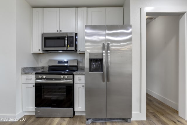 kitchen featuring appliances with stainless steel finishes, white cabinets, and light hardwood / wood-style floors