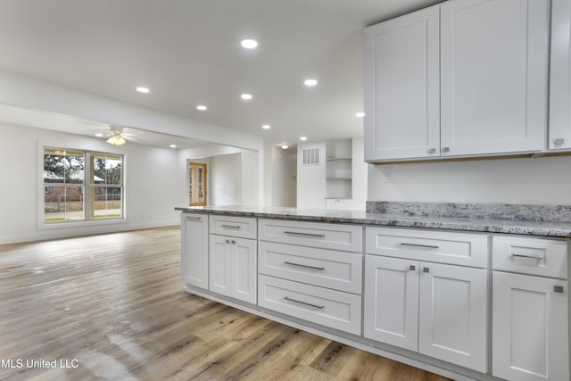 kitchen featuring white cabinetry, ceiling fan, light stone countertops, and light wood-type flooring