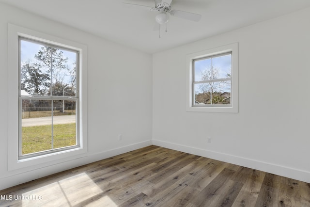 empty room featuring hardwood / wood-style flooring, a wealth of natural light, and ceiling fan